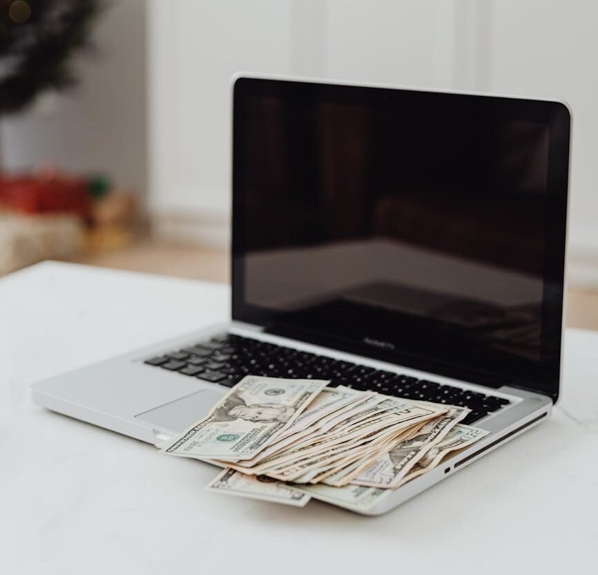 selective focus photo of a silver laptop with banknotes